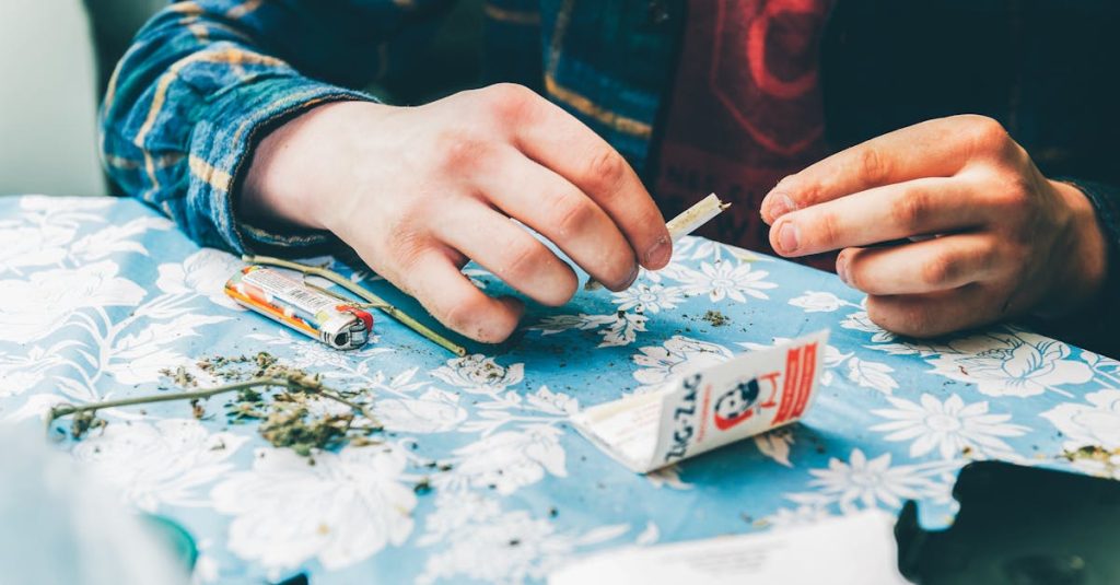 A close-up of a someone rolling a joint with marijuana and rolling papers on a table. How can I talk to my teen about pot? 